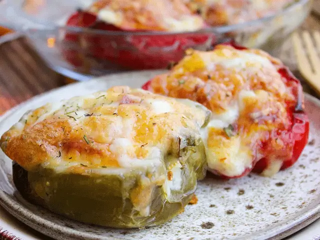 Poivrons rouges et jaunes farcis au fromage gratiné, cuits au four et servis dans un plat de cuisson.